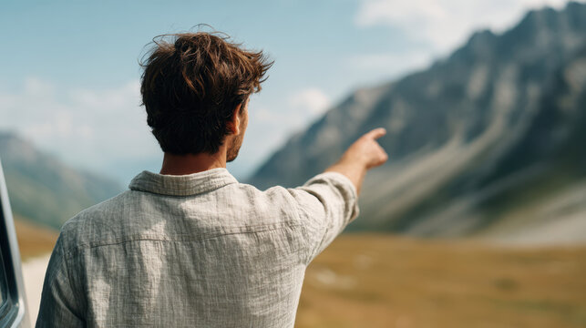 Back view waist up of someone in soft linen shirt pointing at mountain landscape with blurred background and natural light