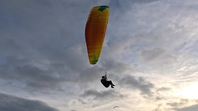 Paraglider flying towards the distant horizon during a beautiful golden sunset
