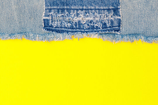 Denim fabric and bright yellow background show the edge of a jeans piece