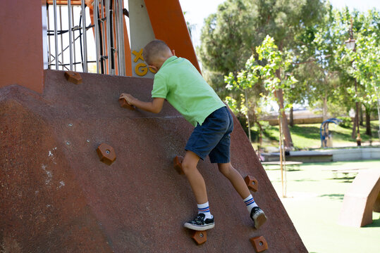 Boy climbing playground wall outdoor active child play