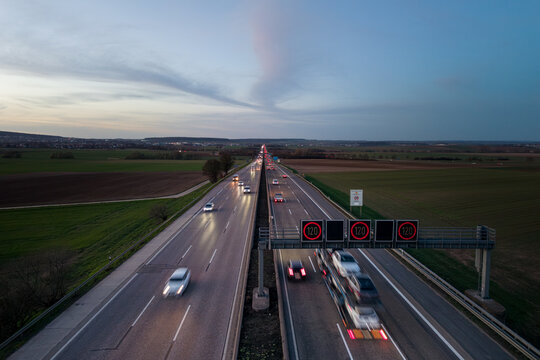 Aerial view of highway with moving vehicles and speed limit signs during dawn