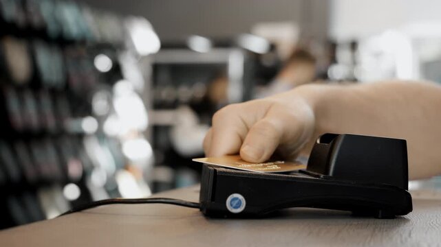 Close up of hand paying with credit card using contactless payment at POS terminal, modern fintech transaction and retail shopping concept.