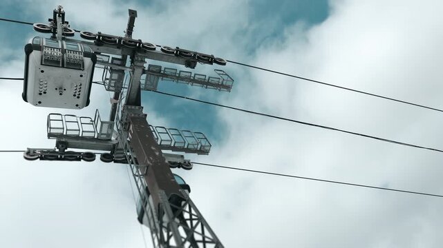 Cable car lift system against cloudy sky at ski resort, mountain transportation infrastructure and travel concept, low angle view.