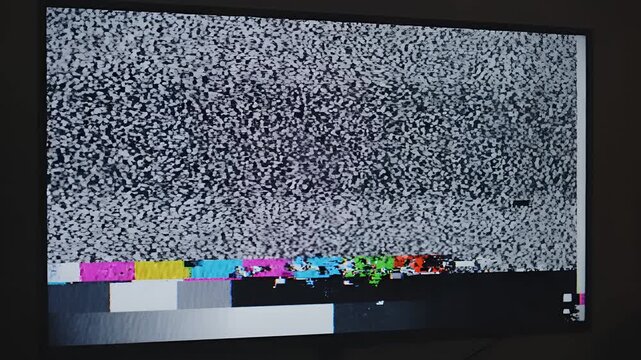 Television screen displaying static and color bars with digital distortion.
