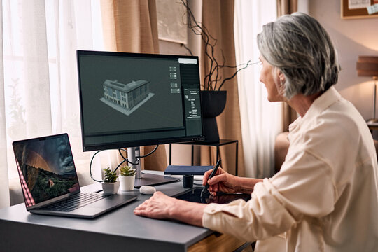 Creative remote work from home. An older woman is creating a 3D architectural building, working on her project from home in a cozy atmosphere.