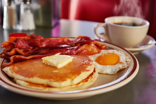 Breakfast With Pancakes, Bacon, Egg, and Coffee at a Diner Table