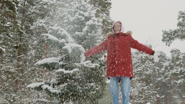 Two diverse male friends pushing African American girl sledding downhill in winter park, cheerful biracial young woman jumping up and tossing snow in air
