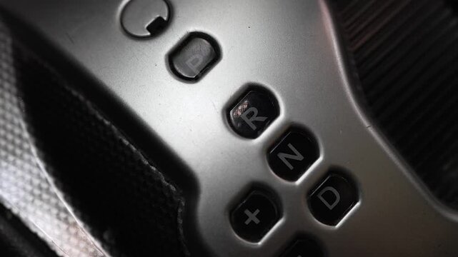 Macro close-up panning shot of an automatic car gear selector showing PRND letters and plus/minus manual shift controls
