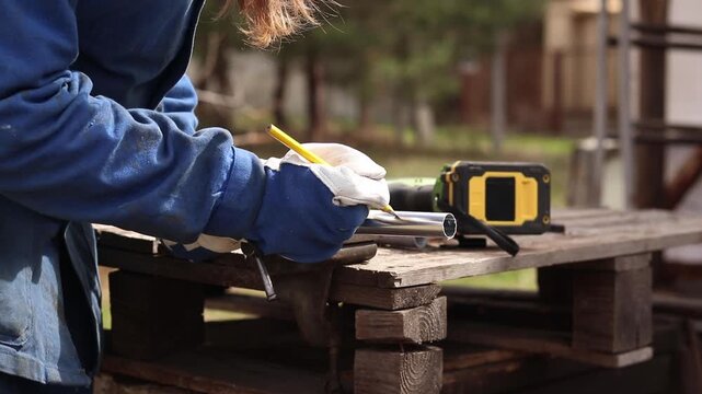 Cordless reciprocating saw cuts metal pipe. A craftsman in protective gloves uses a cordless reciprocating saw (electric knife) to saw a thin pipe. Working with a power tool. Close-up of work