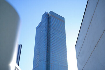 Obraz premium Tall glass skyscraper against bright blue sky