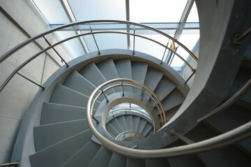 Obraz premium Curving concrete spiral staircase with metal railing indoors