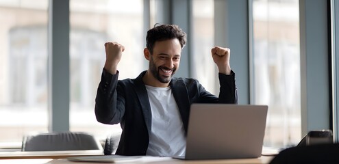 Fototapeta premium Happy Businessman Celebrating Online Success with Laptop in Modern Office Environment.