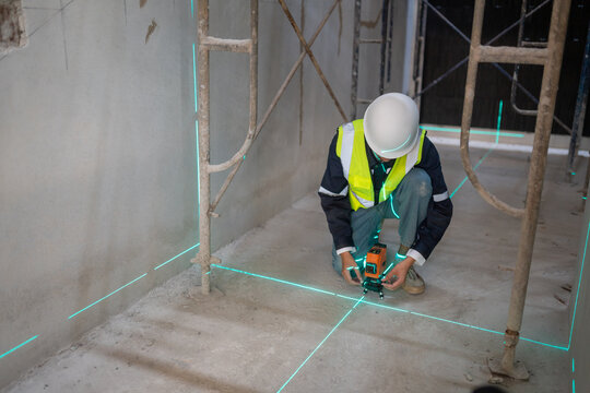 Construction worker using laser level in building site indoor action scene industrial environment focus on precision