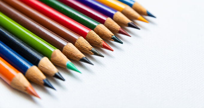 Colorful pencils lined up on a white surface ready for use in art and drawing activities