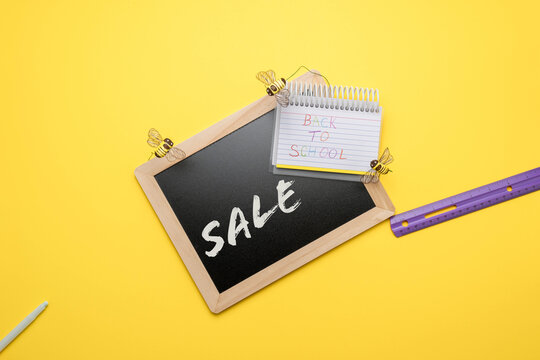Back to school sale template with chalkboard and spiral notebook with lined paper on bright yellow background.