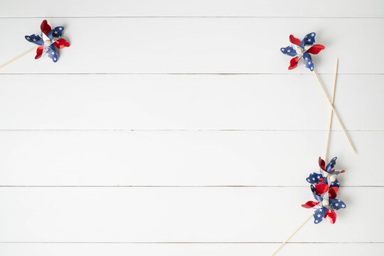 Red, white, and blue pinwheels with stars on a white, wooden surface with space for message text.  American Memorial, Independence, Labor, or Veteran's Day background.