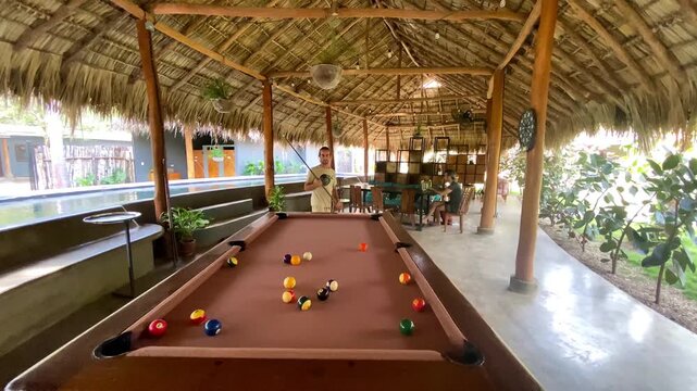 Man Playing Pool Billiards in Tropical Thatch Hut