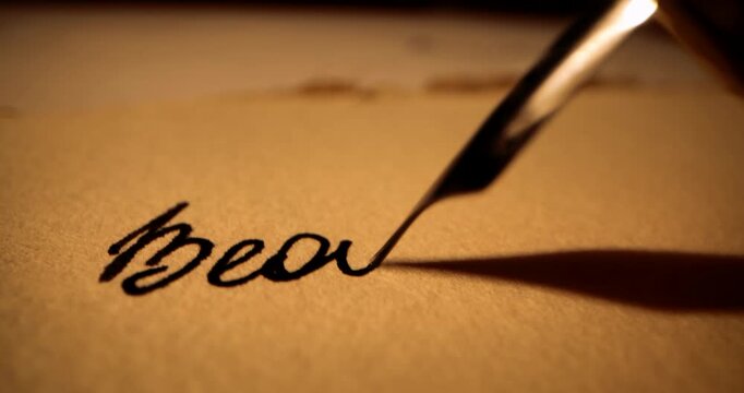 closeup of hand writing letter with vintage quill pen and ink on old parchment paper by candlelight