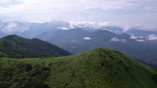 Aerial drone view of lush green mountain hills under dramatic cloudy sky in Kerala, India