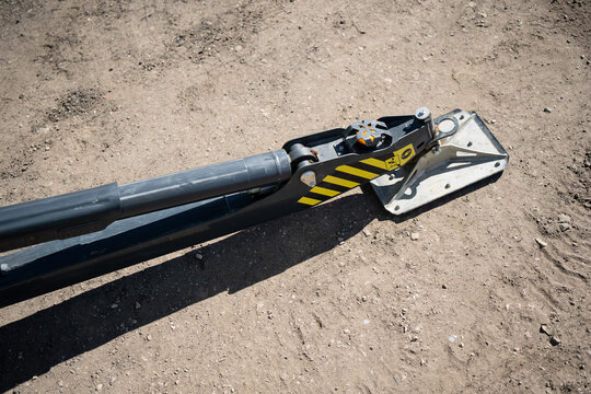Hydraulic stabilizer outrigger with steel foot plate on dirt ground, industrial machine support detail for construction safety, lifting and site setup