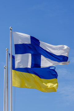 Flags of Finland and Ukraine flutter on the flagpole. The national flag of Finland (white with blue cross pattern) and the national flag of Ukraine (horizontal bands of blue and yellow).  