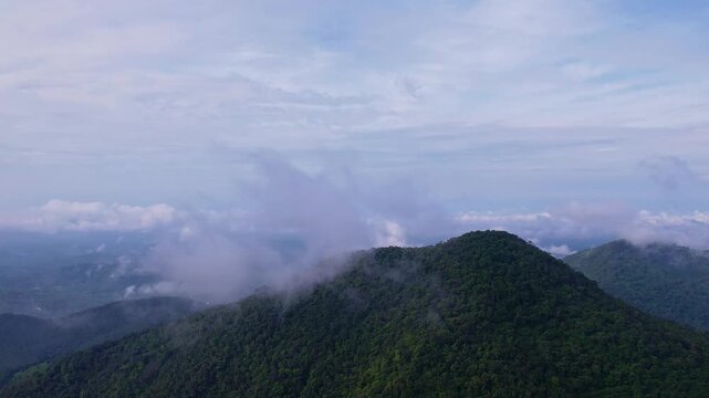 Panoramic view of layered green mountains and deep valley with low clouds drifting above the landscape