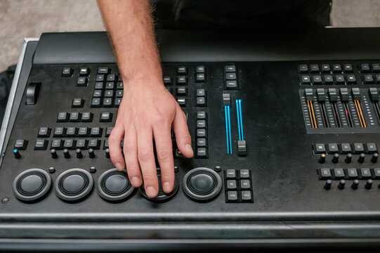 The hands of a lighting technician on the encoders of a Grand MA 3 DMX lighting control console