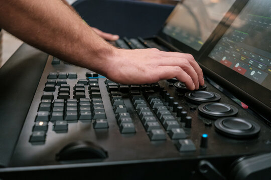 The hands of a lighting technician on the encoders of a Grand MA 3 DMX lighting control console