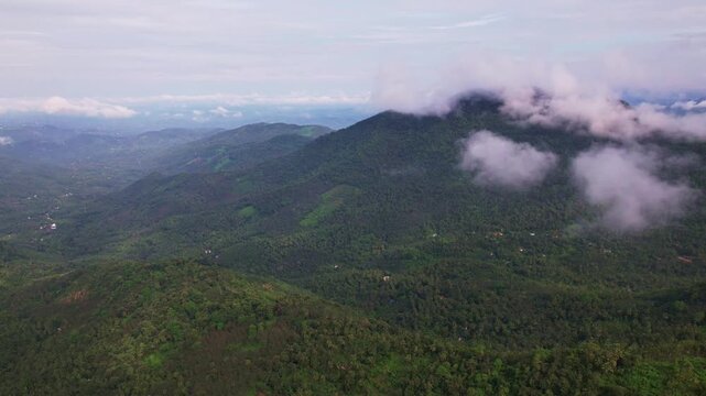 Aerial timelapse of low clouds and mist flowing over green mountain slopes, Fast moving fog drifting across layered hill landscape
