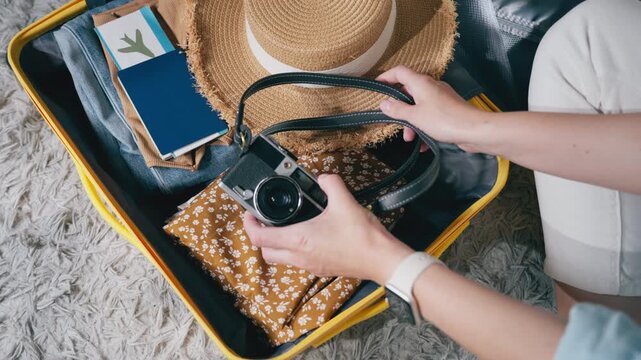 Calm aesthetic scene of woman pack suitcase with summer clothes and travel essentials in soft, minimal lifestyle environment. Concept of slow living, travel preparation, relaxed holiday anticipation