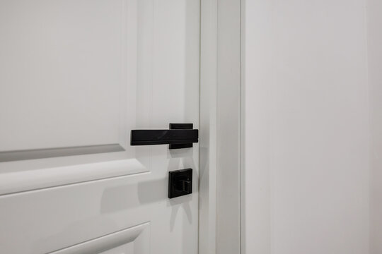 black door handle and light switch next to it in a bright room or office