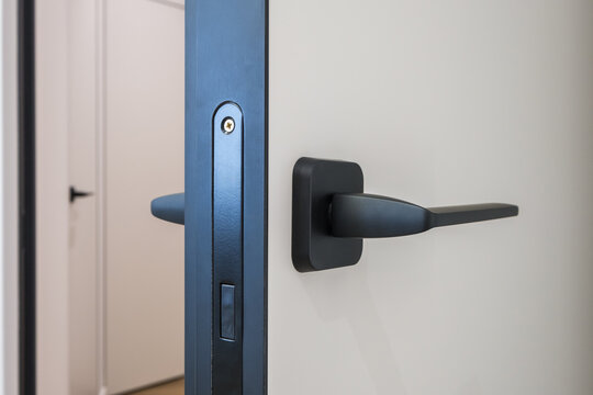 black door handle and light switch next to it in a bright room or office