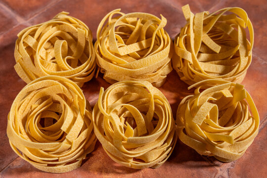 Dry egg pasta shaped in nests on a tile surface 