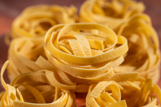 Dry egg pasta shaped in nests on a tile surface 
