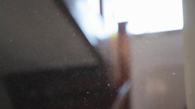 Floating dust particles drift through sunlit air in a dark room, creating a moody atmospheric scene. Tiny specks sparkle in soft light beams, adding texture, mystery and cinematic ambiance.