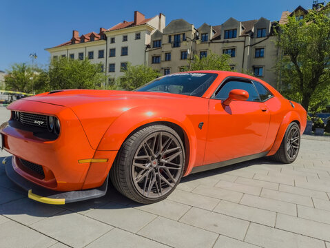 Polska, Ostrowiec Świętokrzyski, 17 kwietnia 2026, 12:10. Czerwony Dodge Challenger Hellcat w wiosennym słońcu. Samoch&oacute;d charakteryzuje się elegancką sylwetką z wydatnymi przednimi błotnikami.