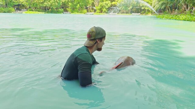 Man Releasing Large Redtail Catfish Back Into Lake Water With Gentle Motion, Catch And Release Fishing Practice In Natural Environment