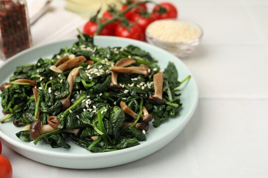 Tasty sauteed spinach with shimeji mushrooms and sesame seeds on light table, closeup