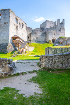 Visitors explore the courtyard of Rabi Castle, the largest castle ruin in Bohemia. The stone walls and wooden structures offer a glimpse into the past in a bright setting.