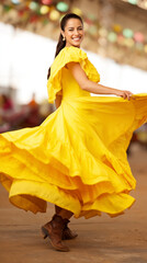 Fototapeta premium Joyful hispanic young female dancing in a flowing yellow dress outdoors