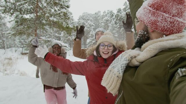 POV of young man with glasses filming video of diverse friends waving at camera enjoying winter scenery in forest