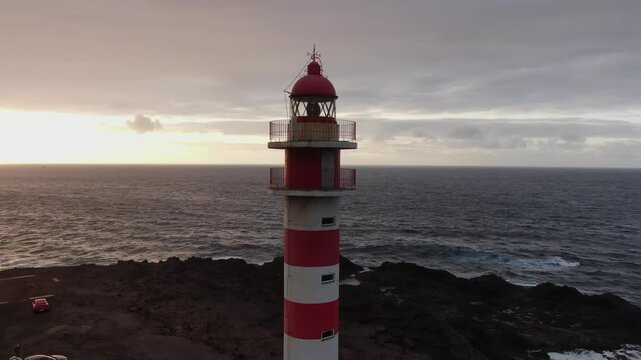 Beautiful aerial view of the Sardina del Norte lighthouse in Gran Canaria. Red and white building on the coast with a dramatic sky