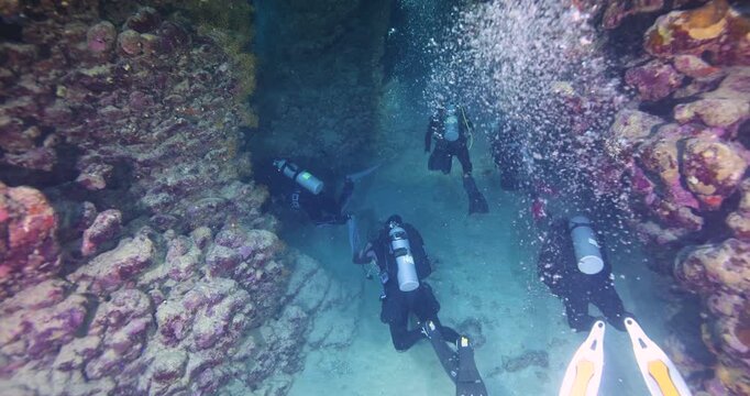 Silhouette of a scuba divers swimming in an underwater cave. A divers explores underwater cave ecosystems. Scuba diving training and education.