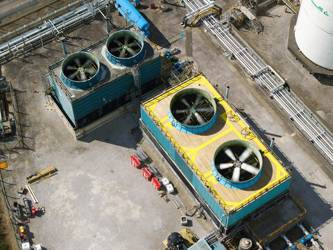 Aerial view of industrial cooling towers with large rotating fans and complex piping systems at the Salt End chemical park Salt End, England, United Kingdom.
