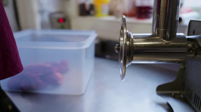 Butcher preparing fresh ground meat using a meat grinder