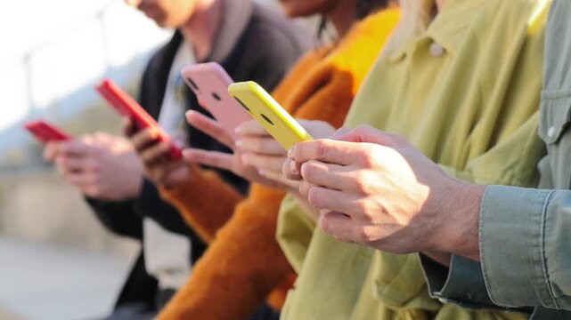A group of diverse individuals deeply engaged with their smartphones, showcasing modern technology and social interaction in a relaxed setting among friends or peers.