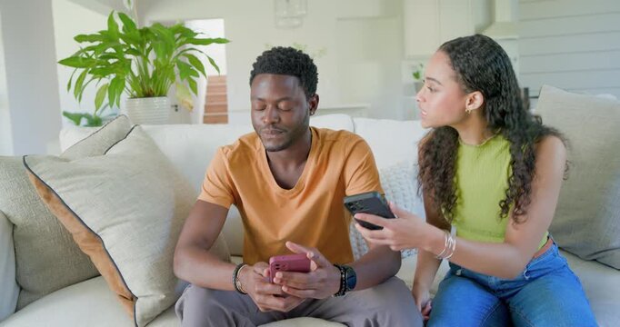 African American couple, woman showing phone, exchanging phones on sofa to compare messages