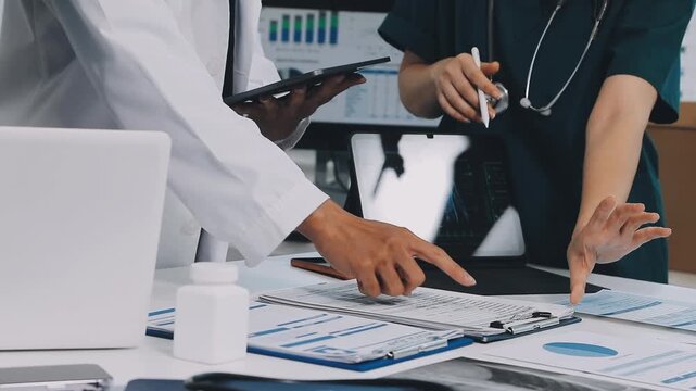 A vibrant red anatomical heart model and a stethoscope on a desk with two doctors having a medical consultation in the background.