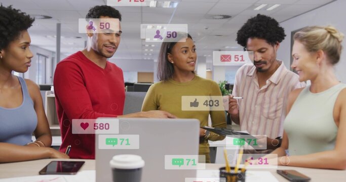 Reviewing five staff in casual tops analyzing laptop and tablet at open office with social overlays