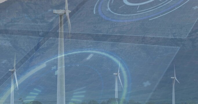 Spinning white turbine towers rising from rocky slope in valley, with HUD overlay